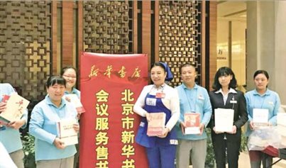薛荣代表（右四）在党的十九大代表驻地售书点与书店工作人员合影。北京发行集团 供图